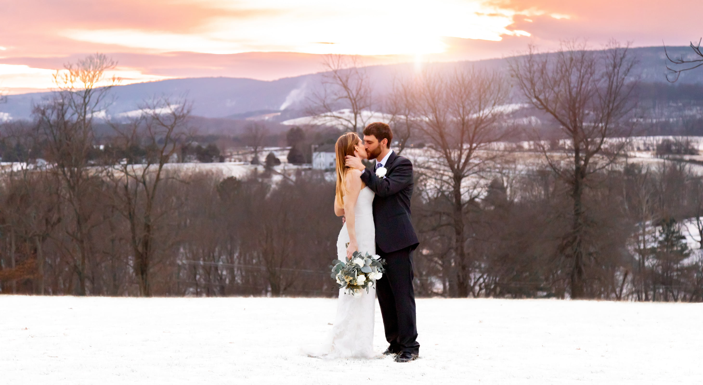 Wedding couple kissing in the snow at sunset